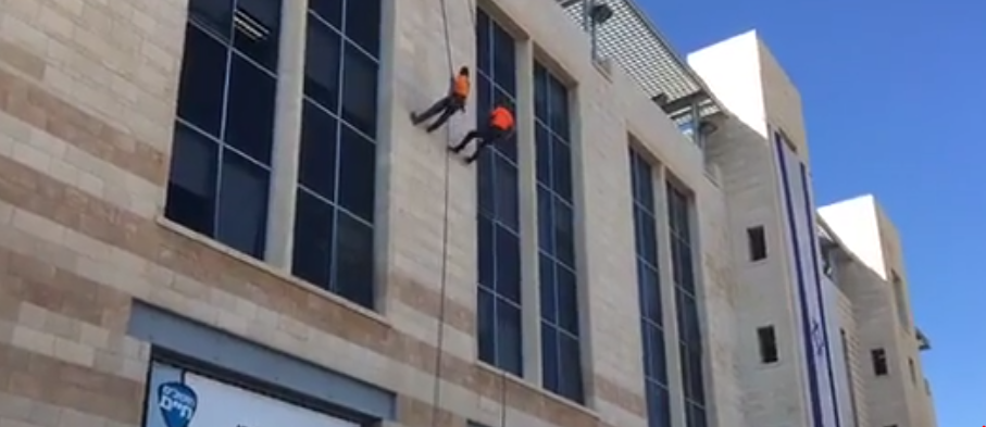 Jerusalem men coming down side of building in Government Square