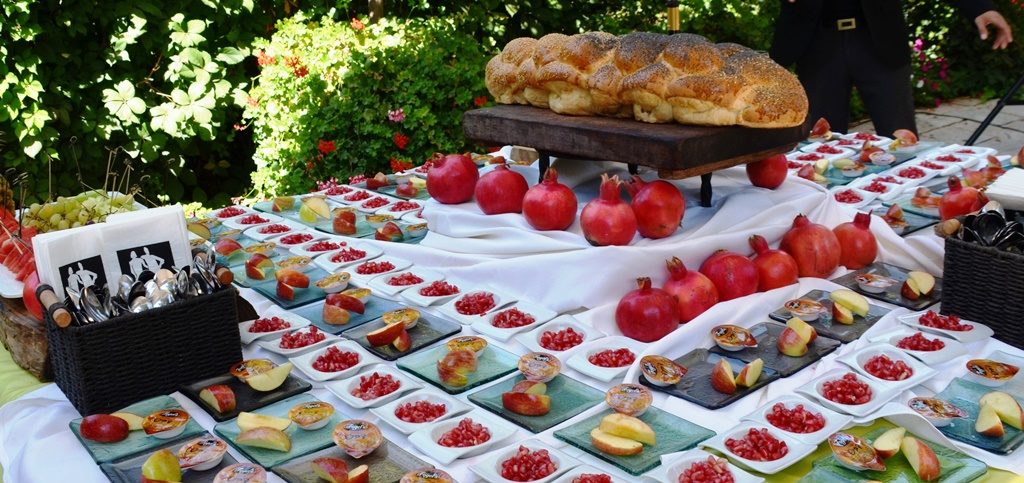 Photo of table with Rosh Hashana pomegranates and apples and honey