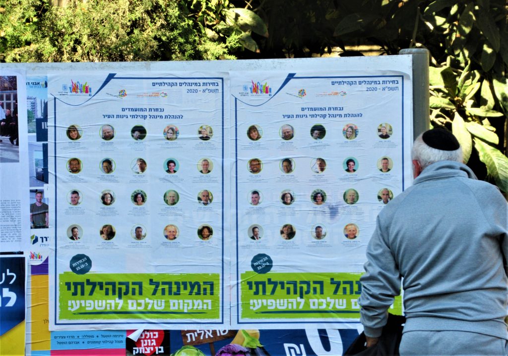 Man reads poster on street for Jerusalem municipal elections 
